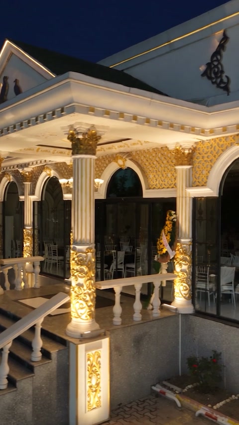 Illuminated classical entrance featuring columns, arches, cornices, and balustrades