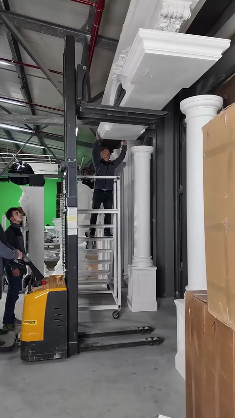 Un addetto si prepara al montaggio superiore della corona d'ingresso incorniciata da colonne.