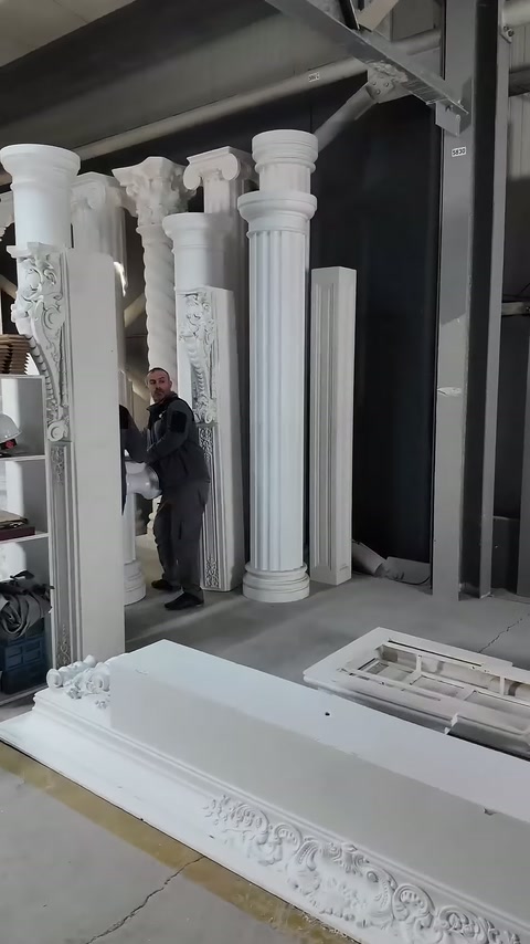 Worker stands among white column models of different shapes.