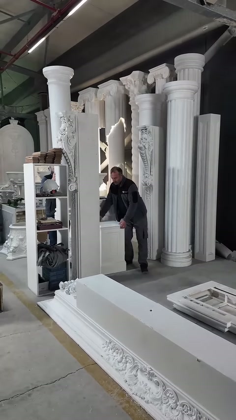 Worker prepares to lift the long decorative column by grasping its base.