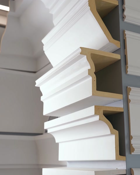 Close-up of white polyurethane cornice profile stack indoors.