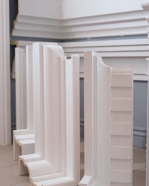Stacked curved polyurethane corner moulding pieces on shelf.