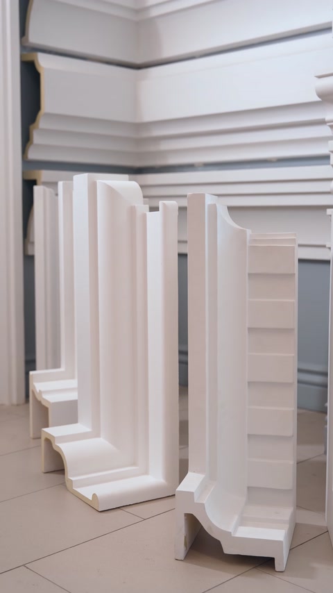 Stacked curved polyurethane corner moulding pieces on shelf.