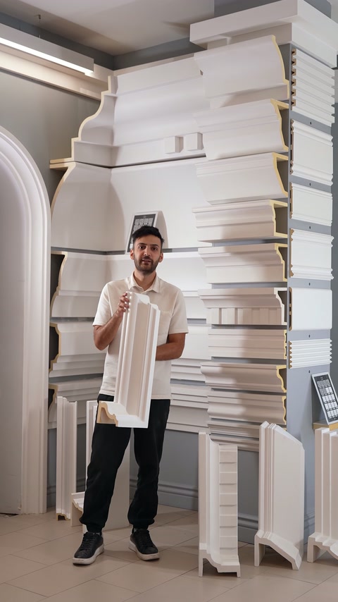 A presenter displays a long fluted polyurethane pilaster moulding indoors.