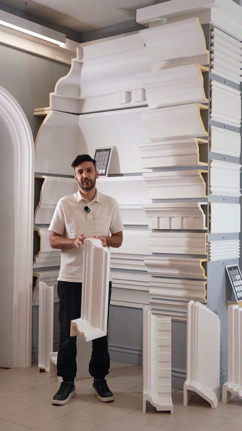 A presenter explains white pilaster trim beside stacked moulding samples.