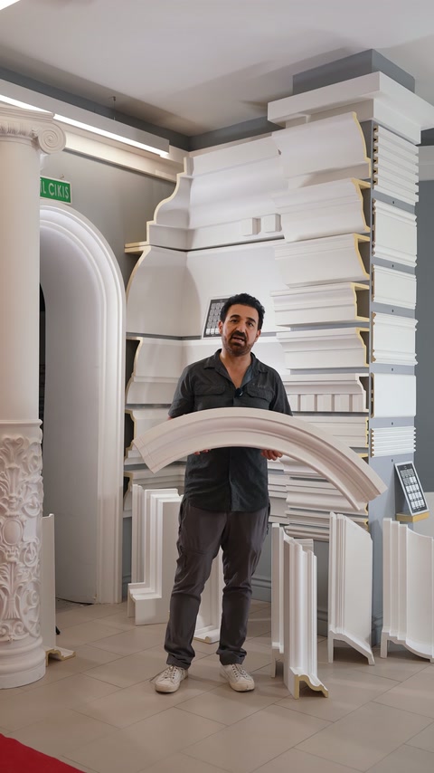 A presenter demonstrates a broad curved arch moulding in the showroom.