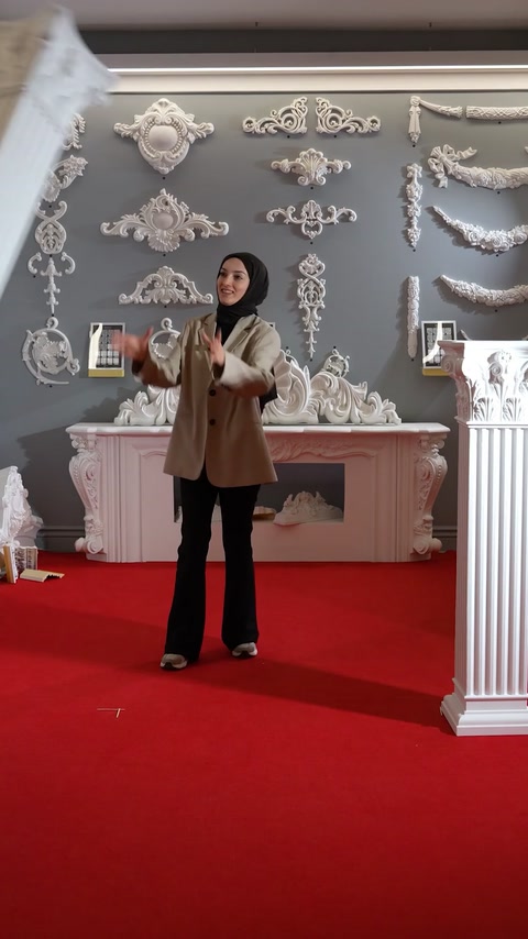 Presenter gesturing beside a fireplace with cornice wall decor