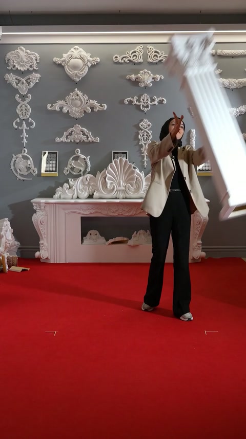 The presenter handles a fluted pedestal column section inside the showroom.