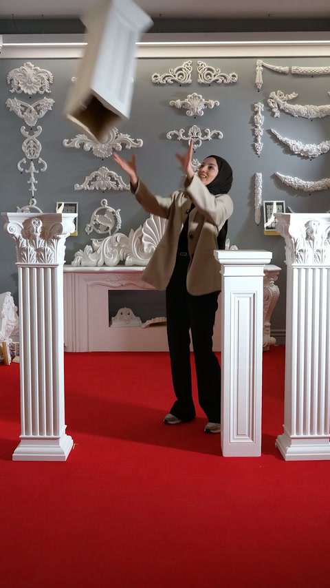 The presenter lifts a pedestal component above the arranged column models.
