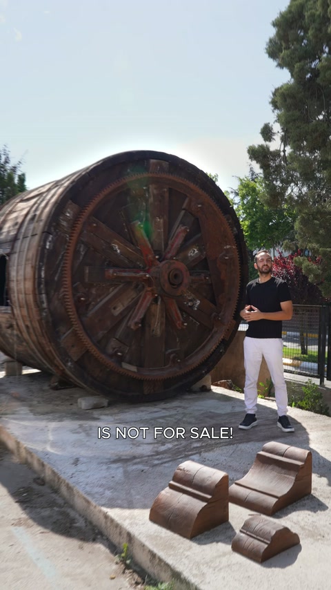 A round wooden structure is displayed with curved decorative profiles in front