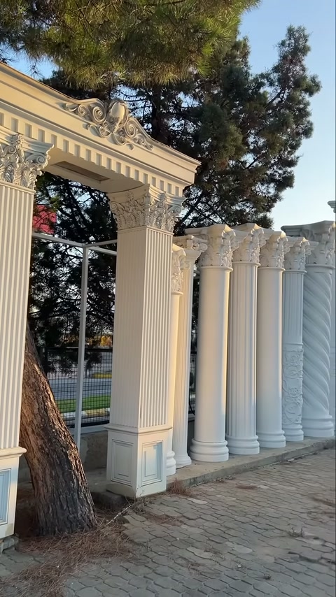 Classical-headed decorative columns arranged in sequence on stone pavement