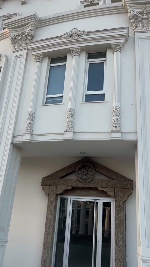 Upper level of classical building featuring columned window frames