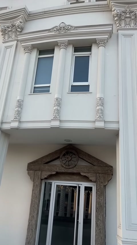 White facade with fluted pilasters and decorated column shafts lined up