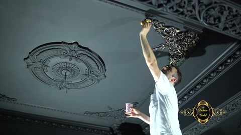 Un artigiano applica la pittura sul rosone decorativo del soffitto