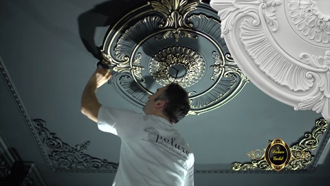 Un artigiano dipinge la sezione decorativa intorno al rosone da soffitto