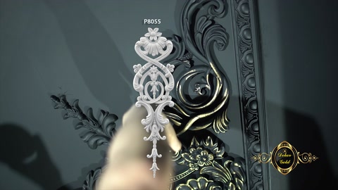 Gold-colored paint is brushed onto a raised decorative motif