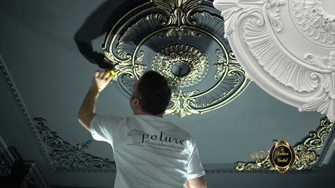 L'artigiano con un pennello lungo colora il perimetro della decorazione da soffitto rotonda