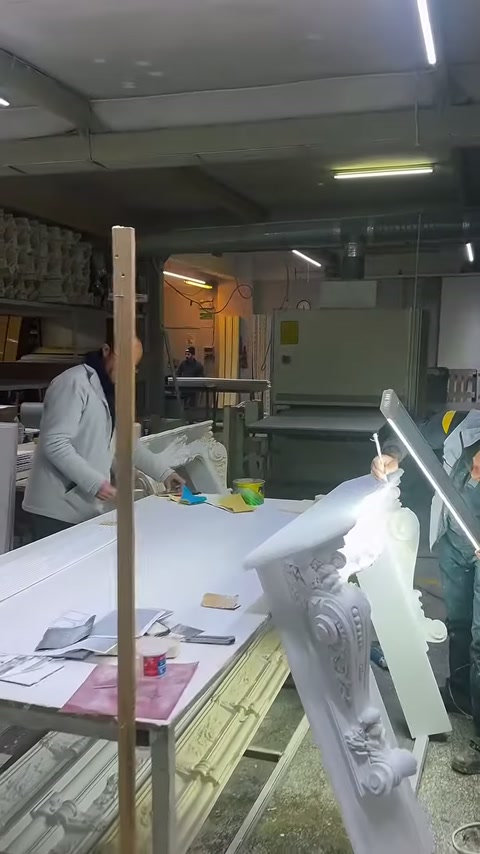 A decorative column capital and white panels are placed on the workshop bench.