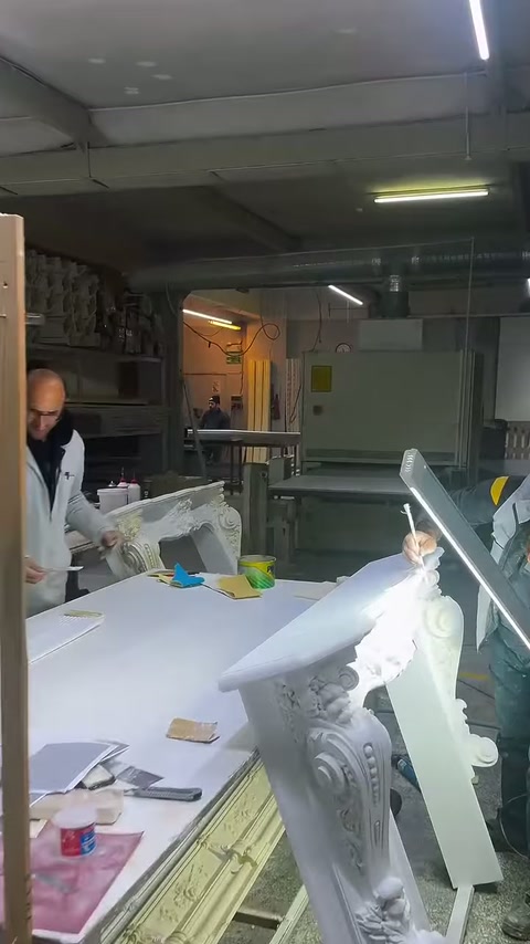 A white decorative column capital waits at the edge of the production table.