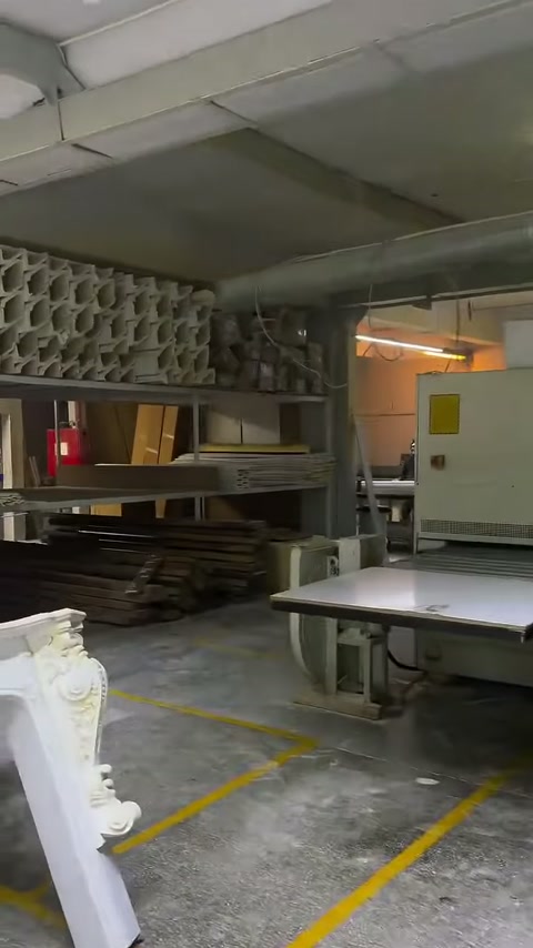 Numerous curved decorative parts are stacked on workshop shelves.