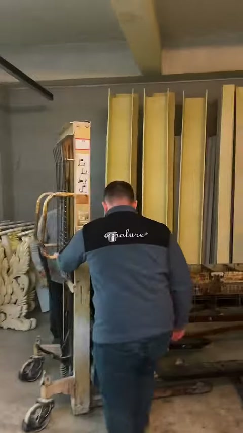 A worker moves a transport cart next to standing parts.