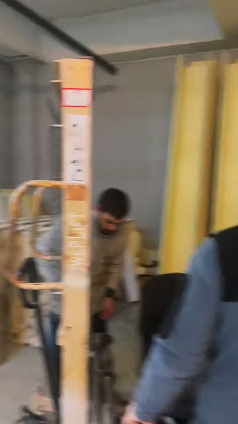 A worker carries a long ornamental profile in an upright position through the workshop.