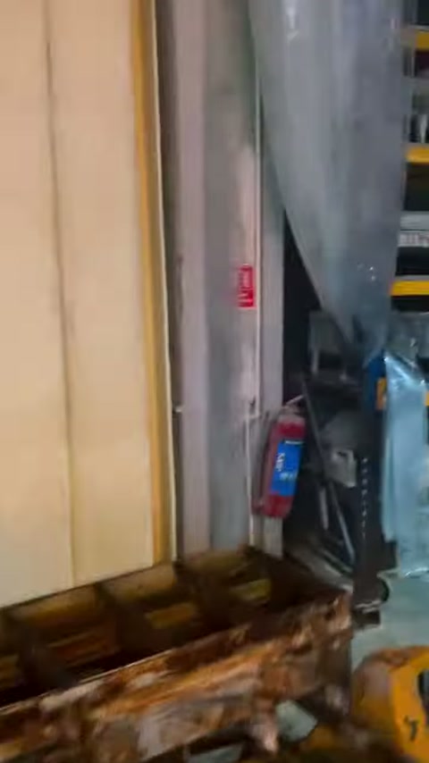 A worker bends in front of yellow panels while handling parts.