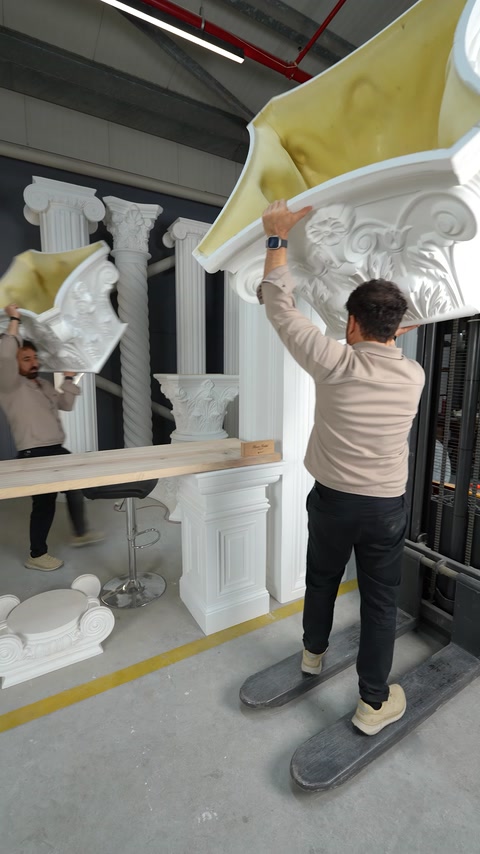 Un artigiano solleva un capitello corinzio decorativo verso il fusto della colonna