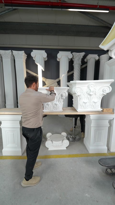 Capitelli bianchi per colonne di forme diverse vengono posizionati su un banco da lavoro
