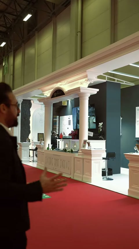 La facciata dello stand con colonne è ripresa dal corridoio fieristico con un'inquadratura grandangolare.