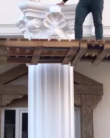 Un artigiano regola la posizione del capitello decorato sulla colonna