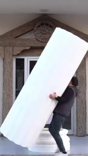 A long white fluted column shaft is brought into an upright position
