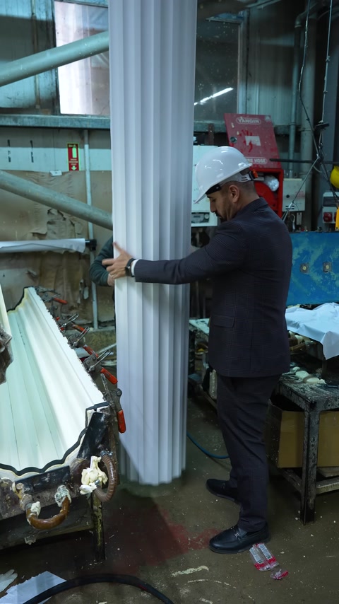 A large fluted decorative column shaft is being inspected in the workshop
