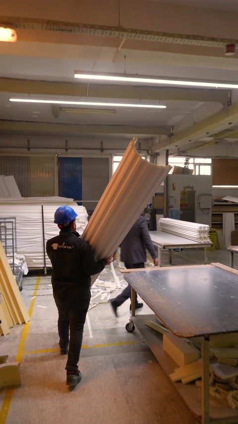 A brown fluted column component is carried through the production area