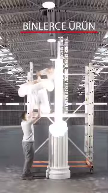 A white column element with a base is being carried by a staff member in the warehouse area.