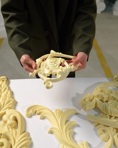 Mani che tengono un piccolo frammento di soffitto decorativo scolpito
