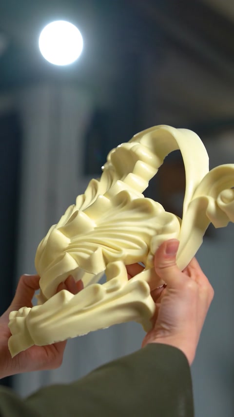 Large curved scroll ornament piece held up close
