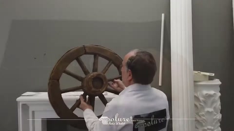 Server touching a dark decorative wheel model on the fireplace mantel