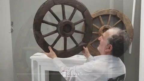Server lifting a dark carriage wheel from the fireplace mantel