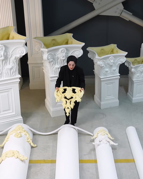 Donna che tiene una modanatura ornamentale color crema accanto a colonne classiche bianche
