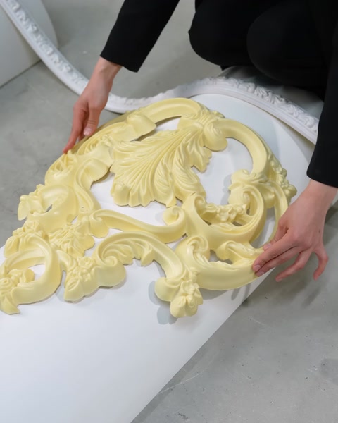 Mani che posizionano una modanatura ornamentale flessibile color crema su una superficie curva