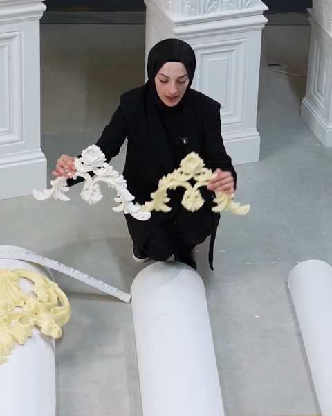 Donna che tiene un lungo pezzo di modanatura ornamentale flessibile con entrambe le mani