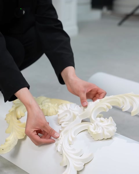 Mani che posizionano frammenti di modanatura flessibile bianca su una superficie curva