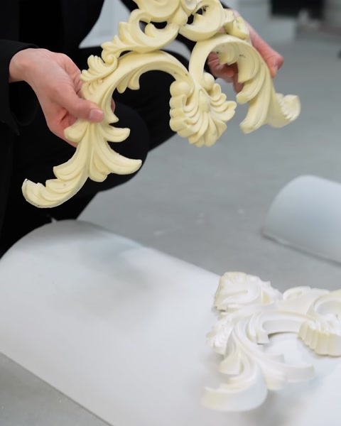 Primo piano di mani che tengono un pezzo curvo di modanatura ornamentale color crema
