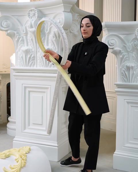 Donna che tiene una modanatura flessibile color crema piegata a forma d'arco