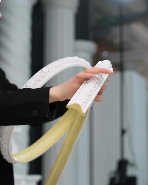 Primo piano di mani che confrontano una modanatura flessibile piegata e una modanatura dritta