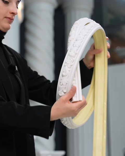 Primo piano di mani che tengono insieme modanature flessibili bianche e color crema piegate