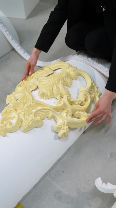 Mani che posizionano una modanatura ornamentale flessibile color crema su una superficie curva