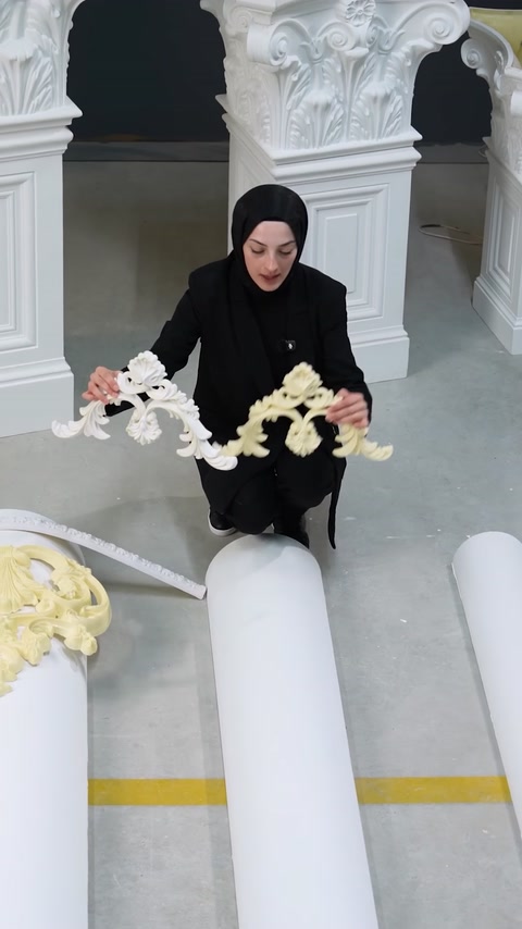 Donna che tiene un lungo pezzo di modanatura ornamentale flessibile con entrambe le mani