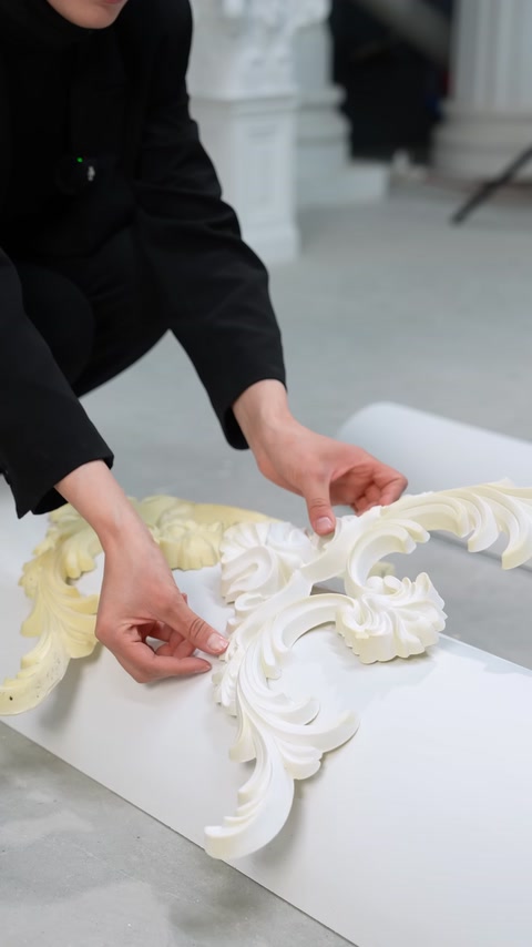 Mani che posizionano frammenti di modanatura flessibile bianca su una superficie curva